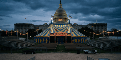 Blue and yellow circus tent with lights and seating stands in front of the U.S. Capitol building at dusk
